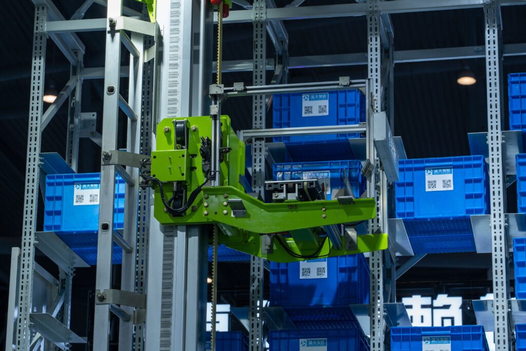 Transstockeur automatisé manipulant des bacs de stockage bleus dans un système de rayonnage grande hauteur au sein d’un entrepôt logistique automatisé.