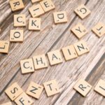 Supply chain : traduction et explication des concepts clés Lettres en bois formant le mot "CHAIN" sur une table, symbolisant les différents maillons de la supply chain et de la chaîne d'approvisionnement.